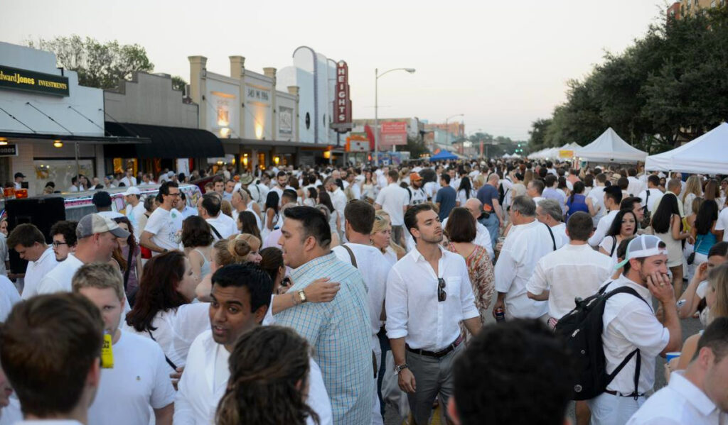 Crowds of people on 19th street in the Heights, dressed in white linen