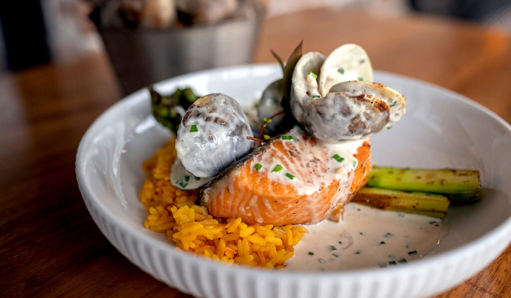 A plate of salmon with oysters and a creamy sauce