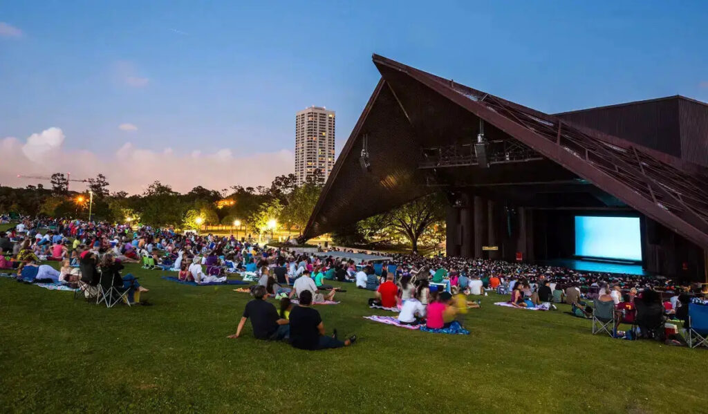 A wide shot of Miller Outdoor Theatre with people laying on blankets on the hill