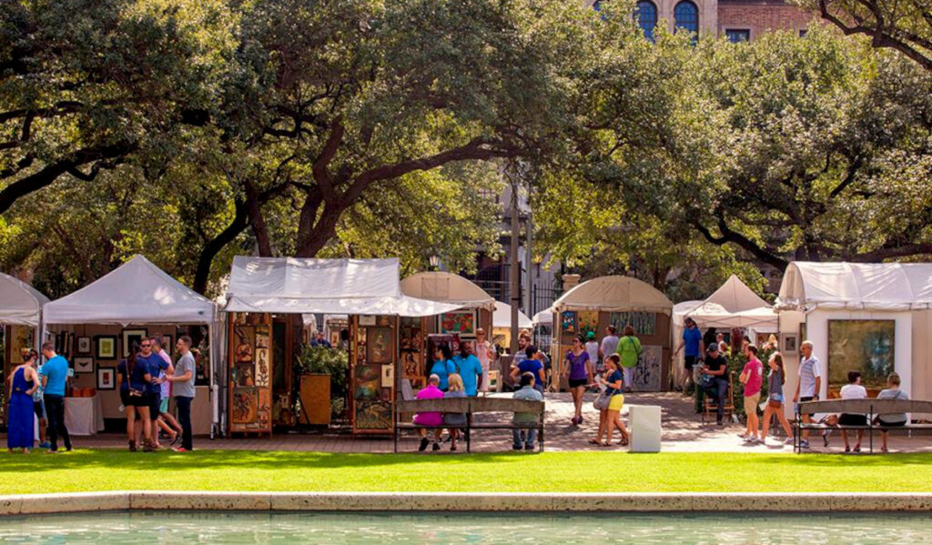 An outdoor market under the shade of a large tree