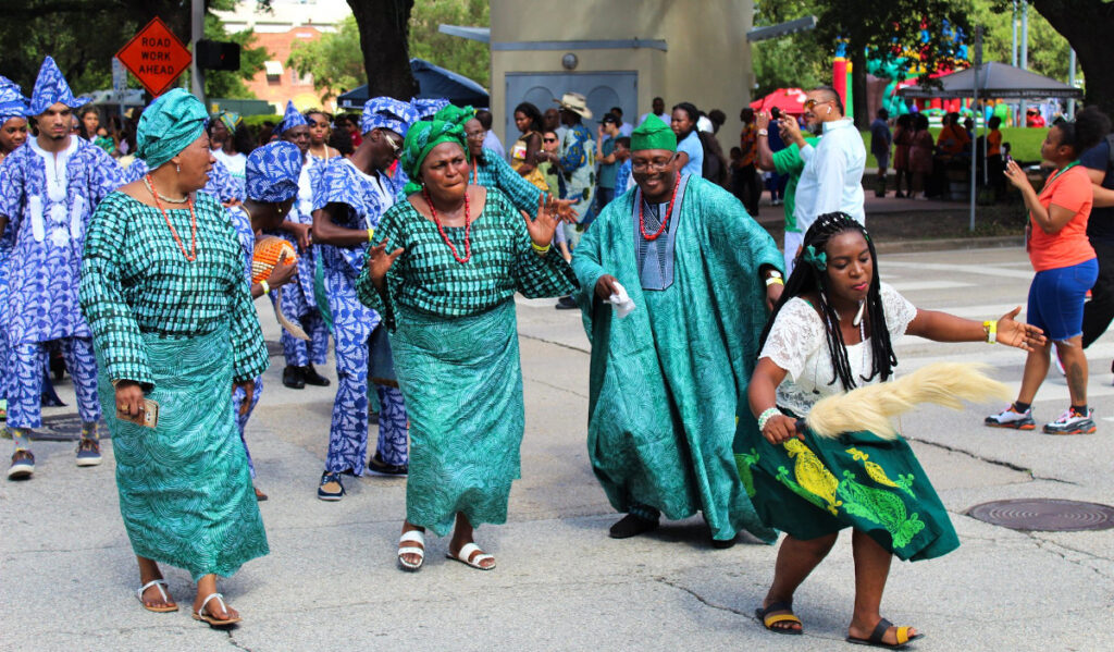 Parade goers in traditional Nigeria dress dance on the street