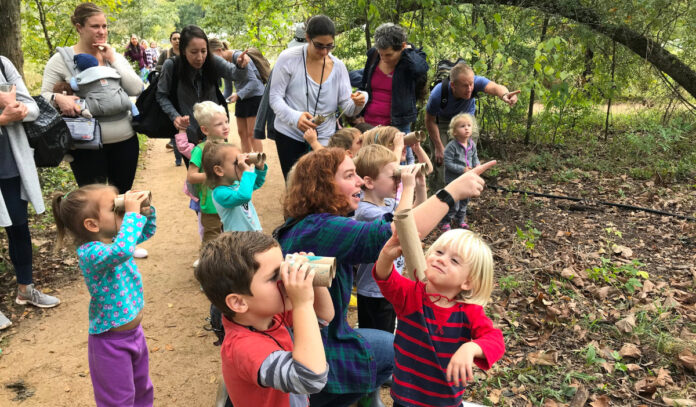 A group of kids and adults look through through the woods