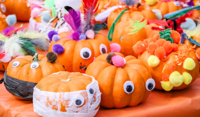 Small decorated pumpkins on a table with googly eyes and puffy colorful balls