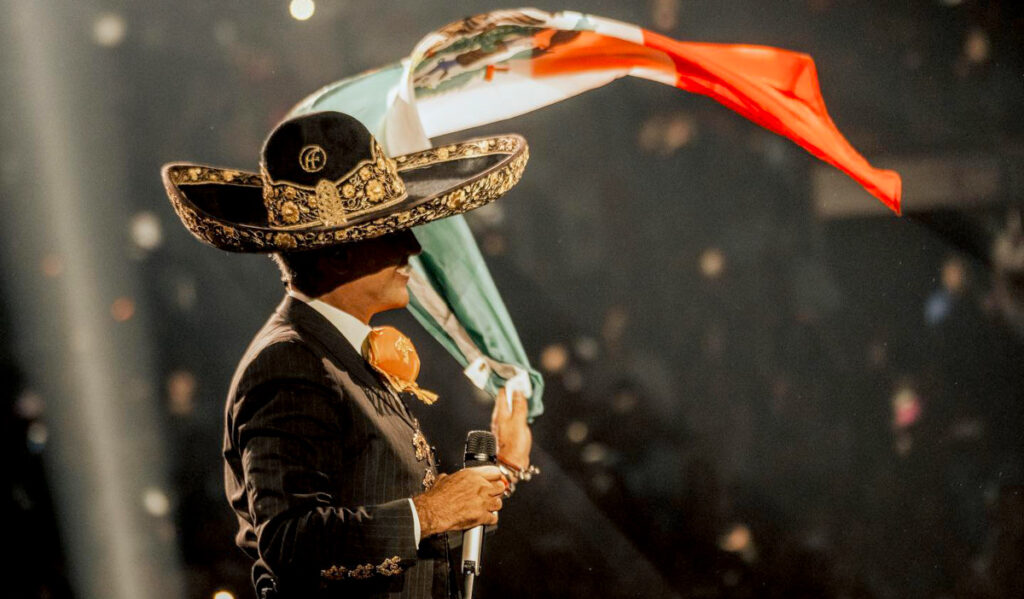 Alejandro Fernandez waves a Mexican flag while performing on stage