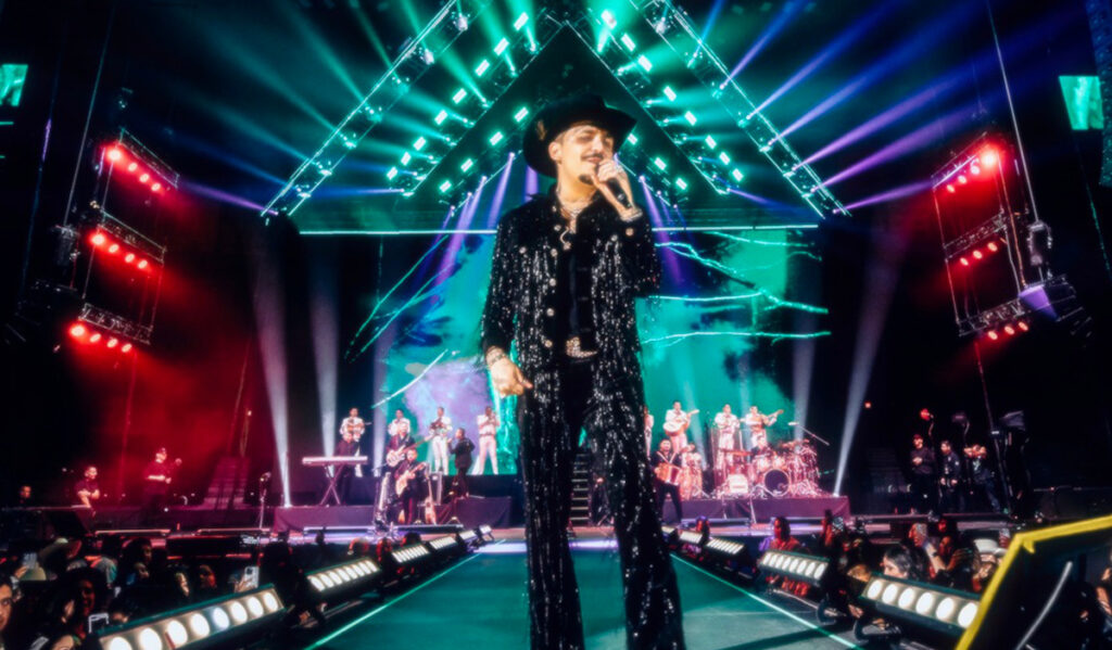 Christian Nodal performs at the front of a stage with his band behind him