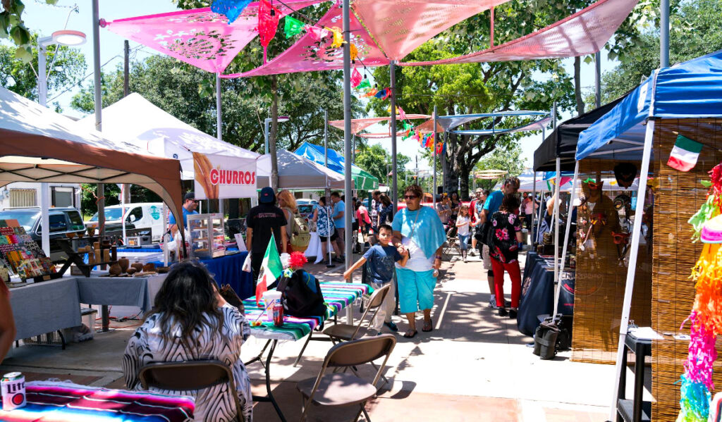 A bustling market with stalls of vendors and people passing through