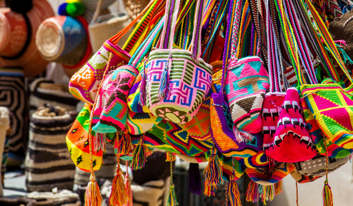 Many colorful bags with complicated patterns hanging in a market stall