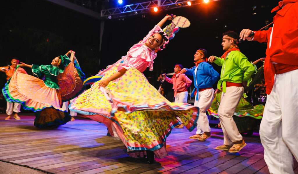 A dancer in a colorful Mexican dress twirls and smiles