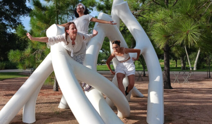 houston-performing-arts-theater-openings-this-week-september-25-october-1-2023-houston-botanic-garden-2 Three dancers dressed in white position their bodies on a white sculpture