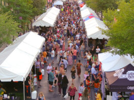 A bustling crowd moving between two rows of tent canopies at a food festival