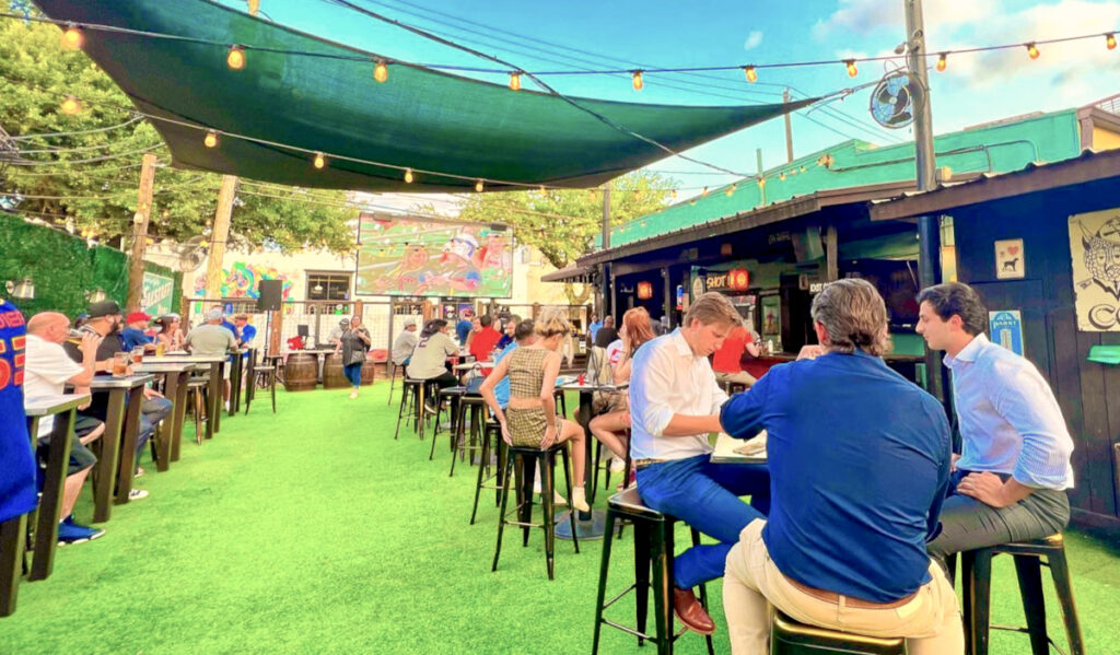 The outdoor patio of Little Woodrow's with bright green turf and tables of patrons