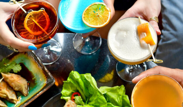 Four colorful drinks viewed from above with appetizers