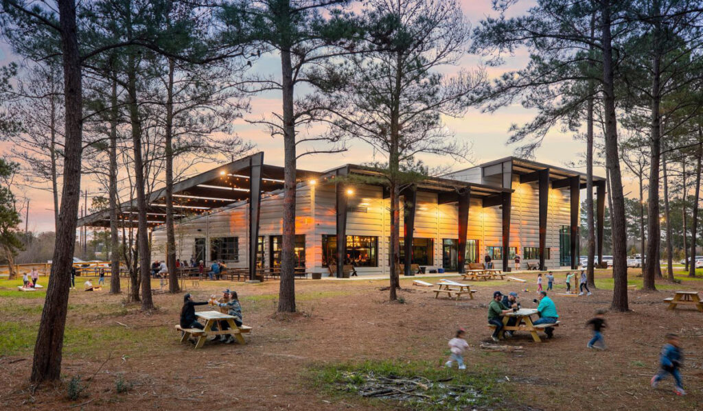 A wide view of the Paradigm brewery along with outdoor seating and people gathered at tables