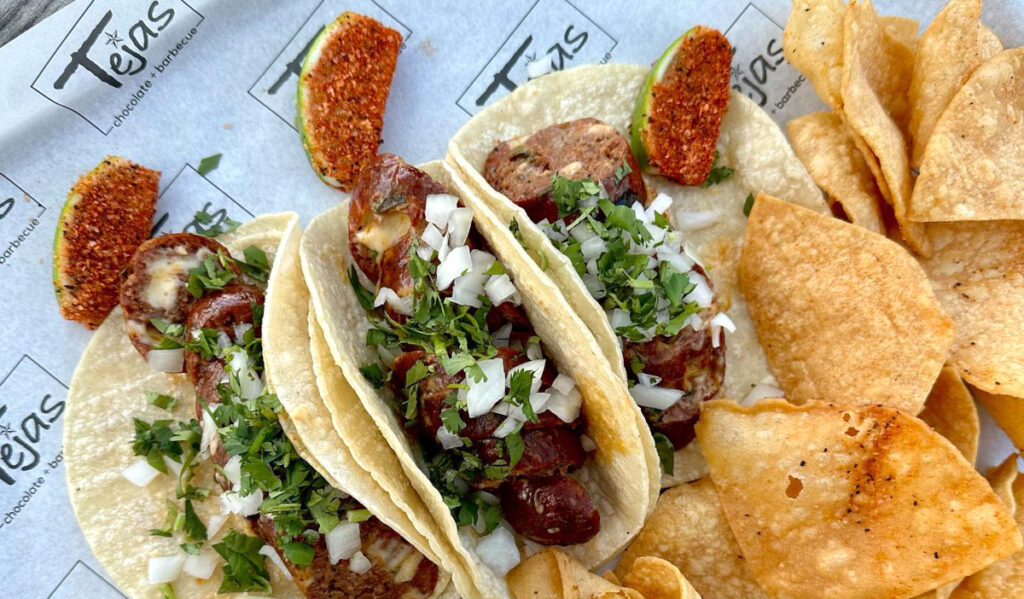 Three tacos filled with smoked sausage, onions and cilantro