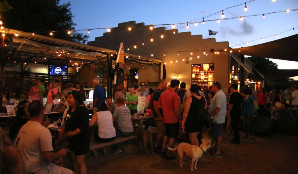 The outdoor patio of Cottonwood at sunset with people and dogs scattered around