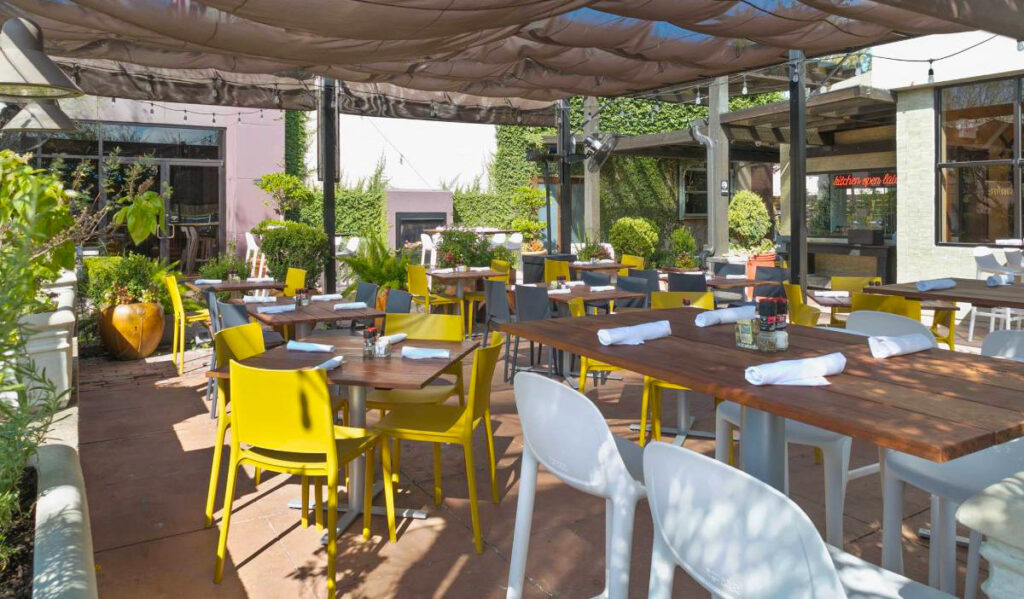 The outdoor patio of Hungry's with mesh covering and plants around the perimeter