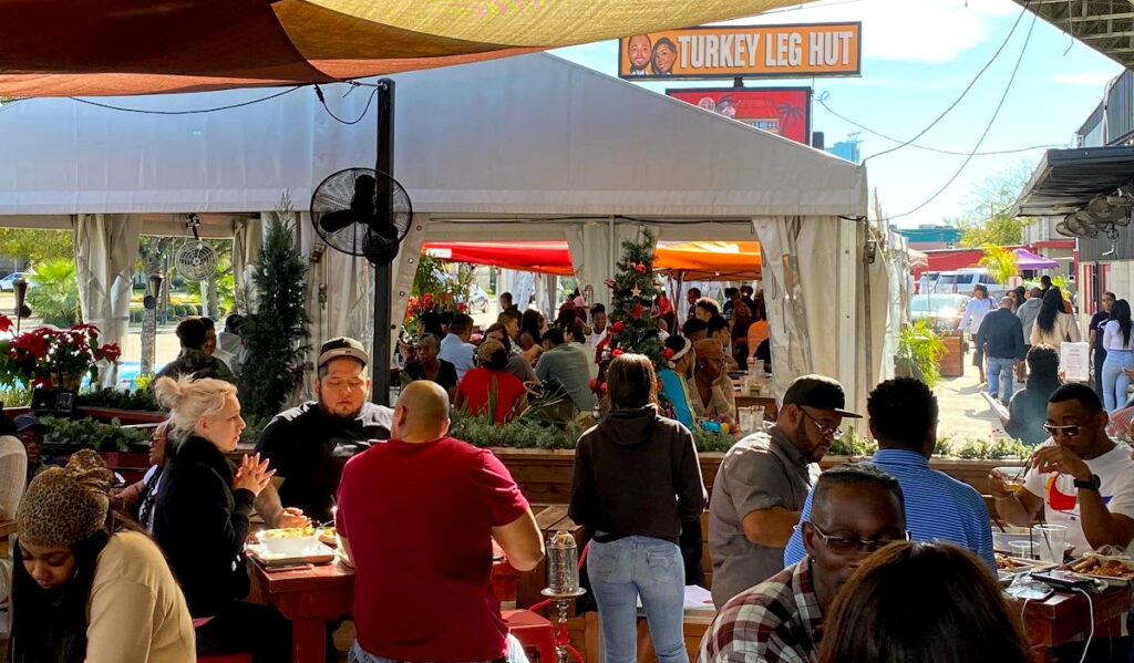 Crowds eat under tent canopies on the patio of Turkey Leg Hut