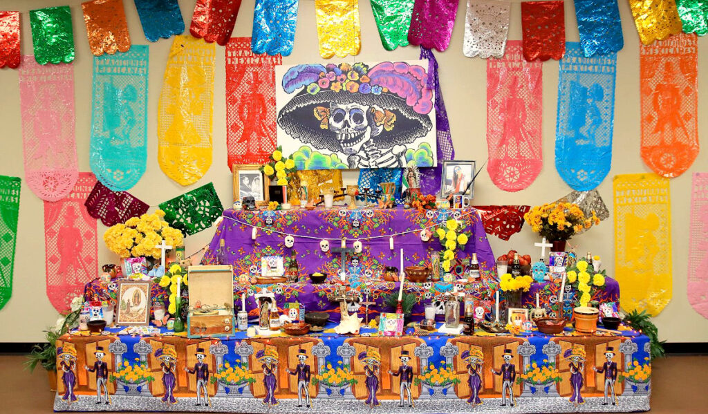 A colorful ofrenda with candles, photos and other altar items