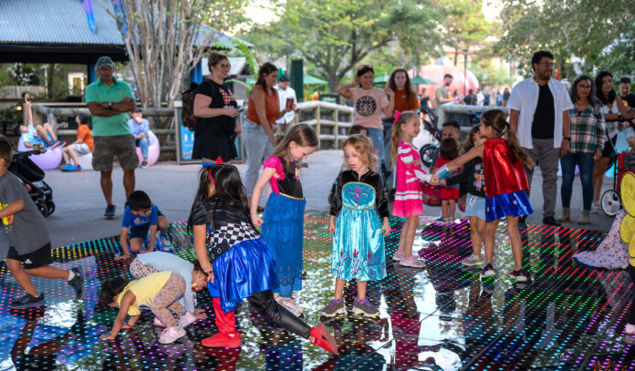 Kids in Halloween costumes on a colorful dance floor