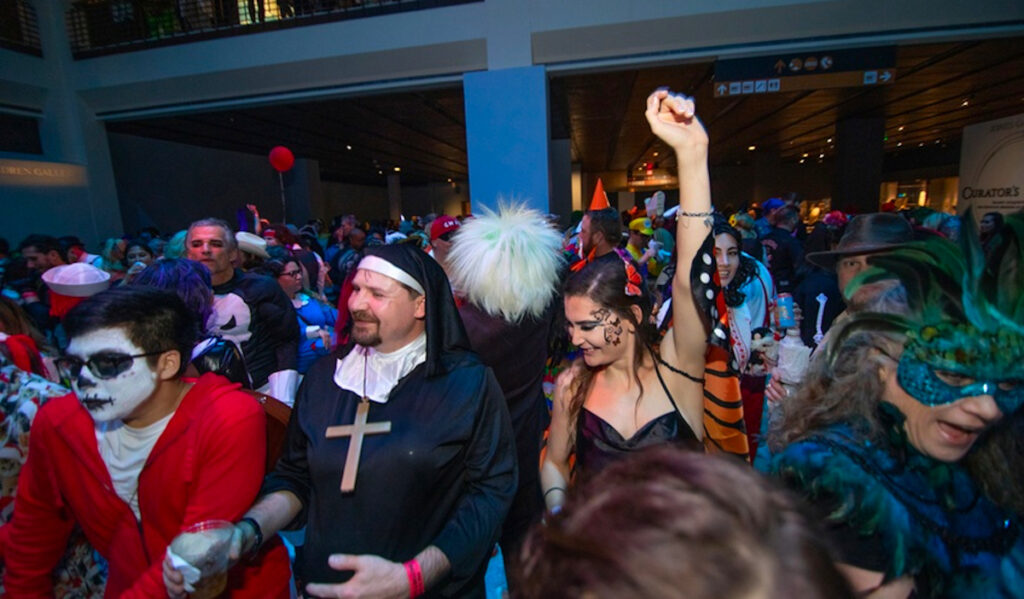 Costumed party goers dance in a museum