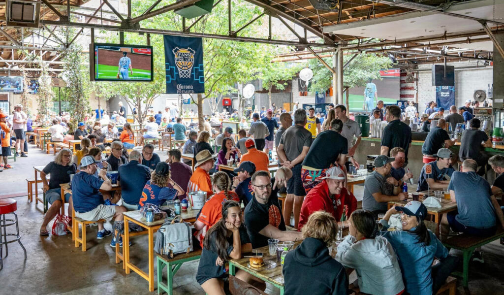 The outdoor patio of Pitch 25 filled with patrons watching Astros on TV