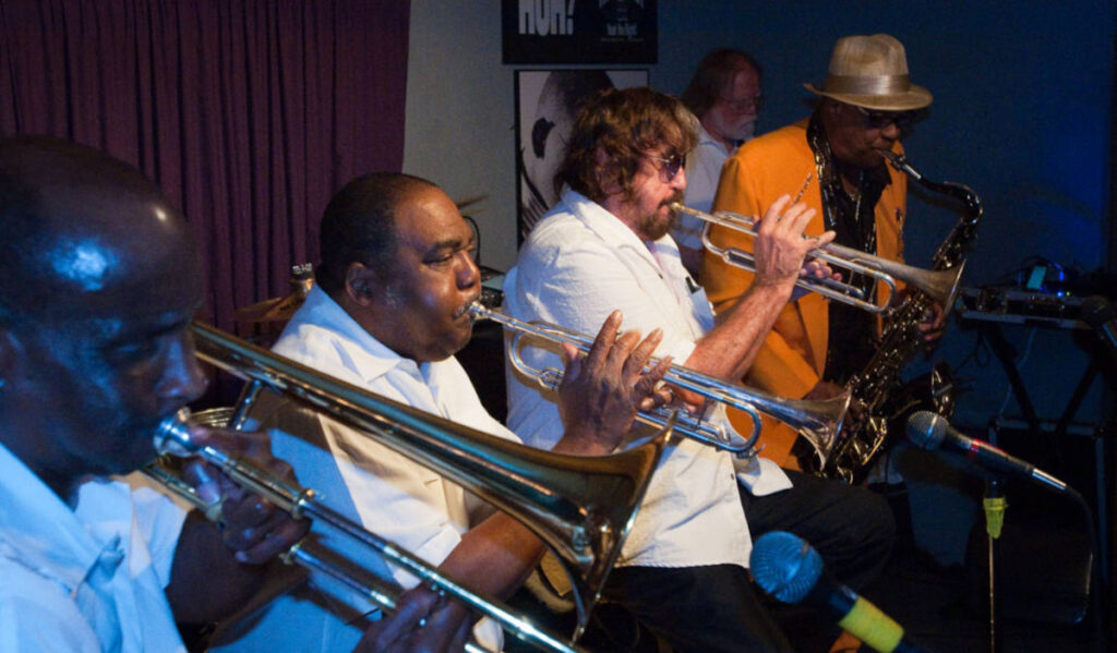 Three trumpeters and a saxophone player perform on stage