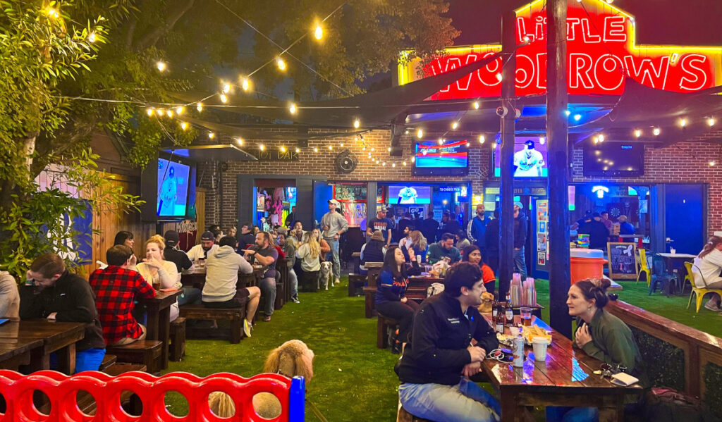 The outdoor patio of LIttle Woodrow's at night with crowds at tables 