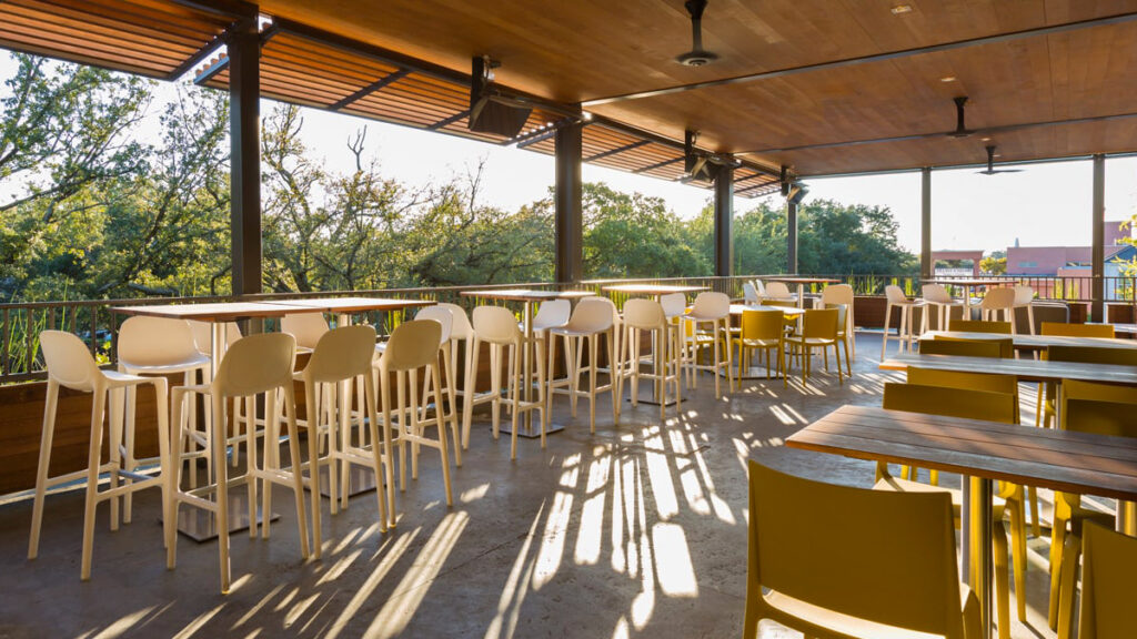 A covered upstairs patio with the branches of live oaks next to it