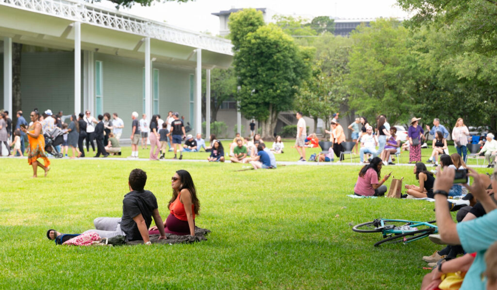 People sitting on blankets on the Menil lawn and walking around