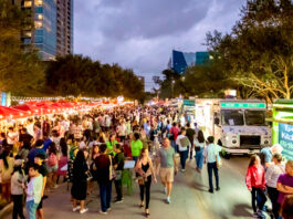 A bustling outdoor market with booths on the left and food trucks on the right