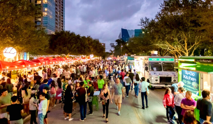 A bustling outdoor market with booths on the left and food trucks on the right