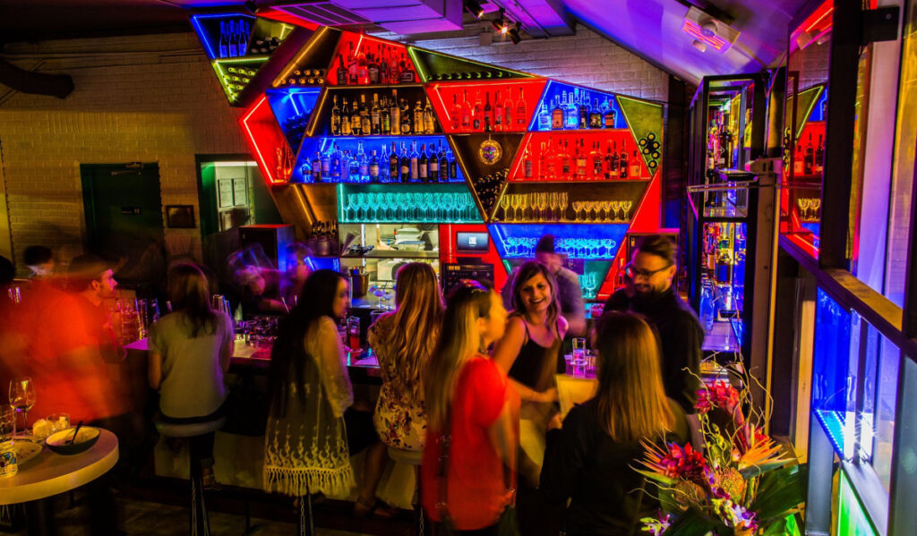 Patrons gathered at a bar with bright red, blue and yellow decor