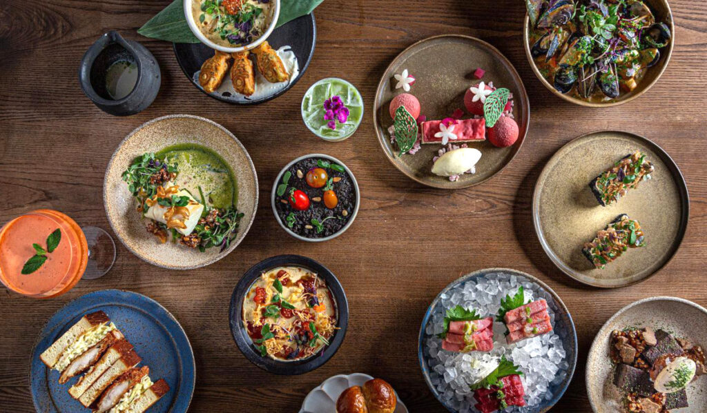 An overhead view of several plates of colorful food and cocktails