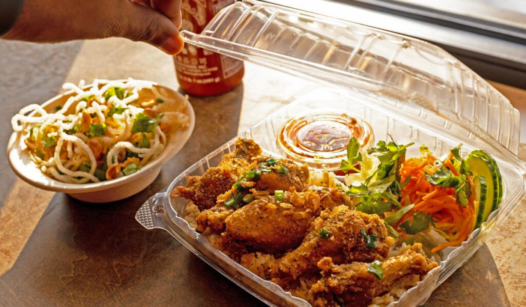 An open box of fried chicken wings and sides in golden sunlight