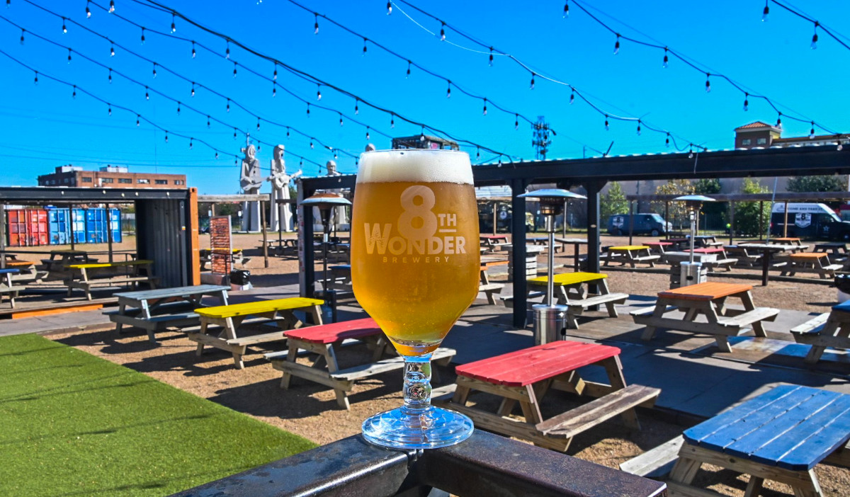 A full glass of beer on a railing with a large patio behind it