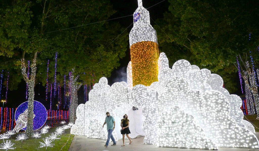 Two people emerging from a tall launching rocket light display