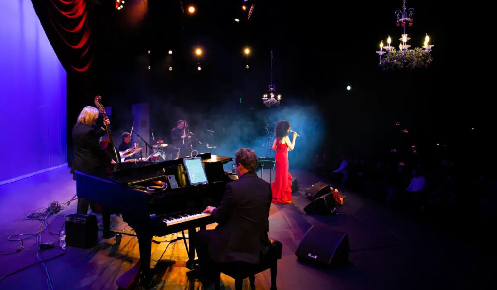 A performer in a red dress sings, accompanied by her band