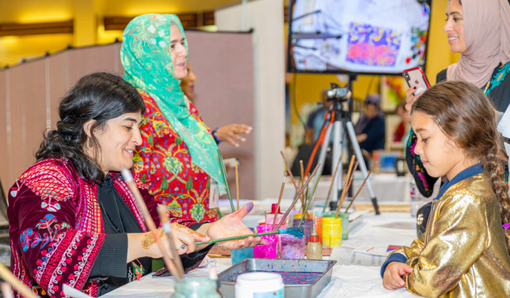 A woman showing a child a paintbrush during an art activity