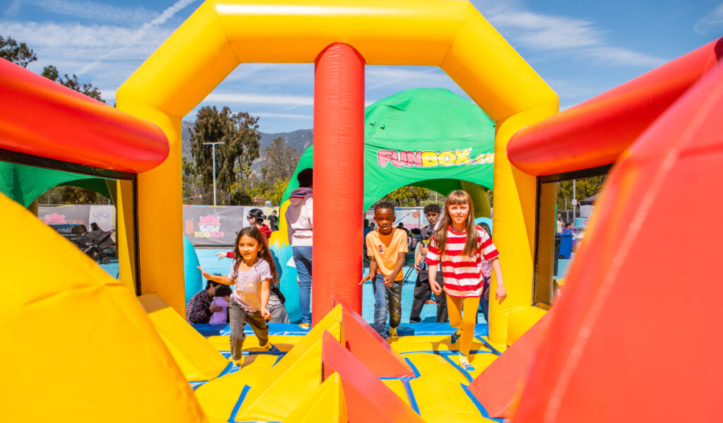 Children running into a yellow and orange inflatable bounce park 