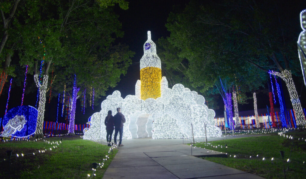 Two people approaching a tall light display of a rocket launching