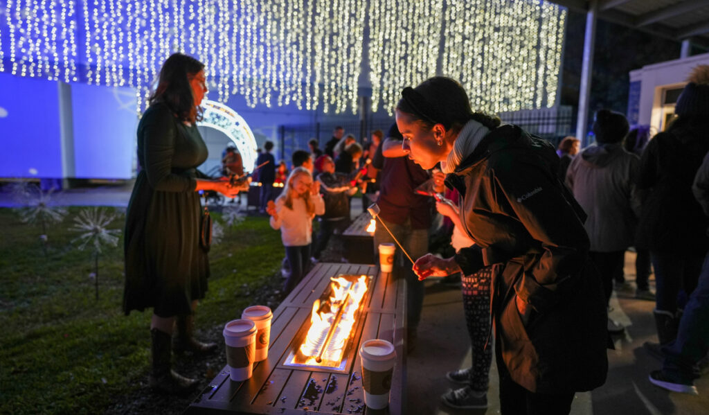 A woman holding a marshmallow over a fire pit