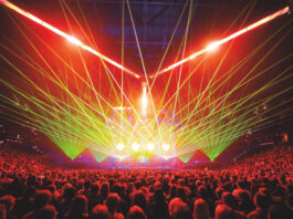 Green and red laser lights cast out from a stage over a crowd
