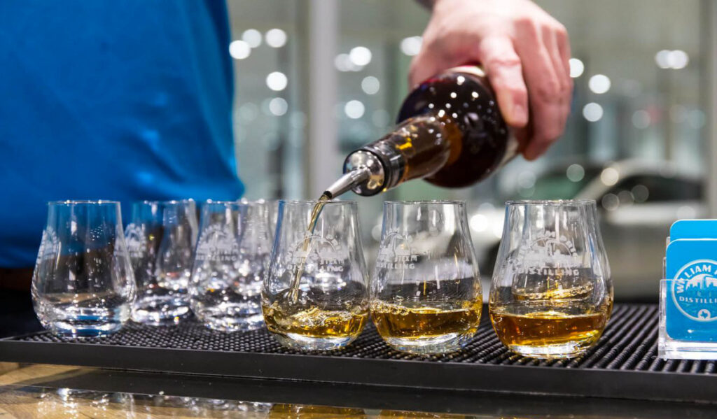 A person pouring whiskey samples into glasses