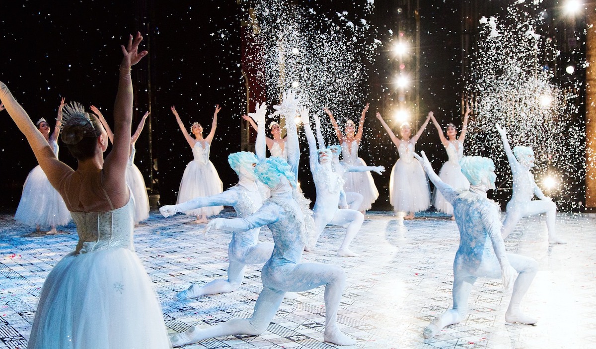 A view from on stage as ballerinas form a ring around performers tossing white confetti in the air
