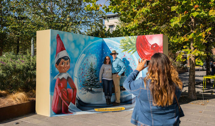 Two people posing in front of a holiday-themed display