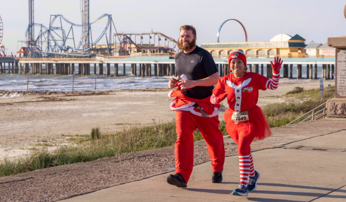 Two runners smiling at the camera with the Pleasure Pier in the background