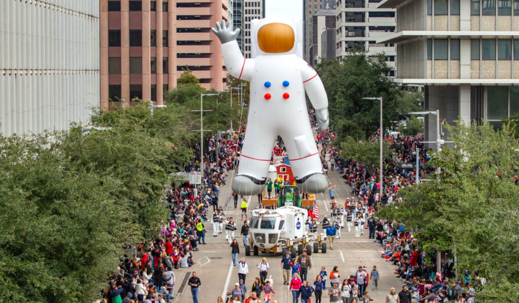 An astronaut float parades on a Downtown street
