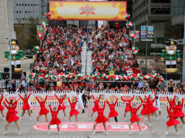 Rows of dancers performing in red dresses with a snowman