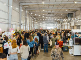 A bustling market scene inside a long warehouse building