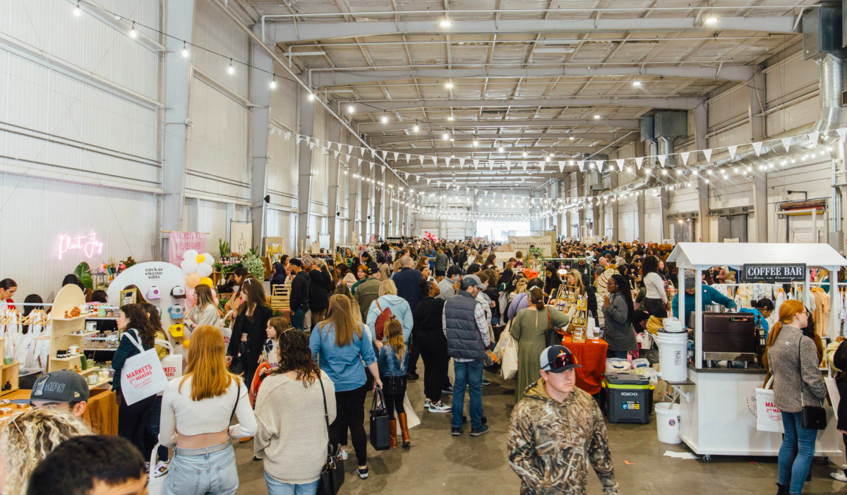 A bustling market scene inside a long warehouse building